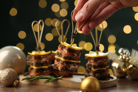 Tasty canapes with cheese on wooden table against blurred lights, closeup. Bokeh effectの写真素材