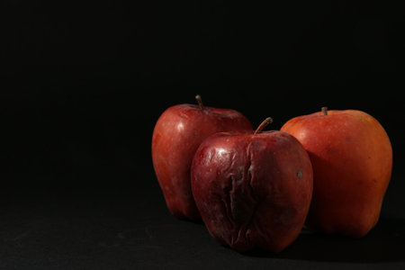 Damaged red apples on black background. Space for textの写真素材