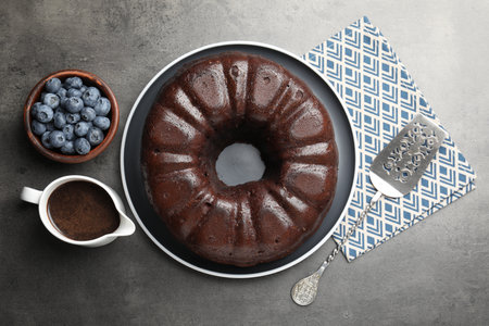 Tasty chocolate bundt cake, blueberries and server on grey table, flat layの写真素材