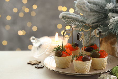 Tasty canapes and festive decor on white table against blurred lights, closeup. Space for textの写真素材
