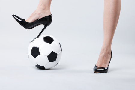 Woman in high heeled shoes with soccer ball on light background, closeupの写真素材