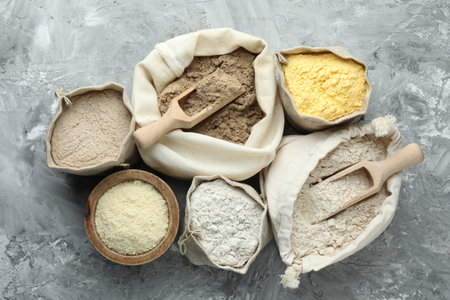 Different types of flour in bags on grey textured table, flat layの写真素材