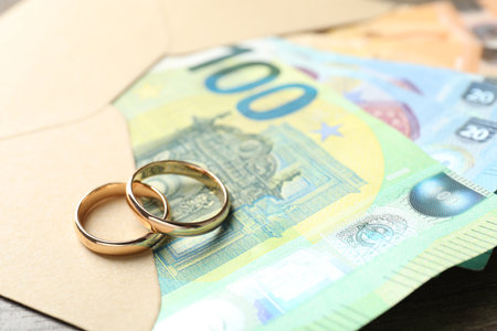 Gold wedding rings, envelope and euro banknotes on wooden table, closeupの写真素材