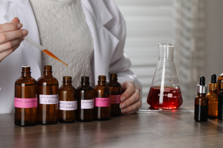 Professional perfumer developing luxury perfume at wooden table in laboratory, closeupの写真素材
