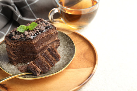 Piece of delicious chocolate cake with mint and tea on white table, closeup. Space for textの写真素材
