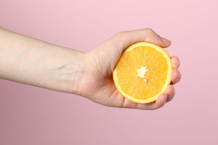Woman with orange on pink background, closeup
