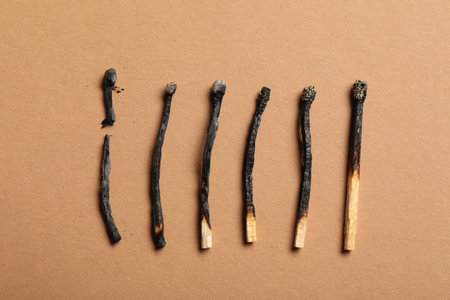 Burnt matches on beige background, flat lay