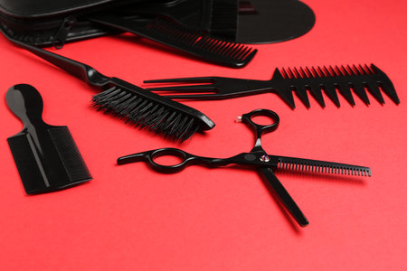 Different hairdresser's tools on red background, closeup