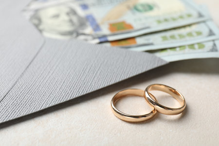 Two gold wedding rings, dollar banknotes and envelope on white table, closeupの写真素材