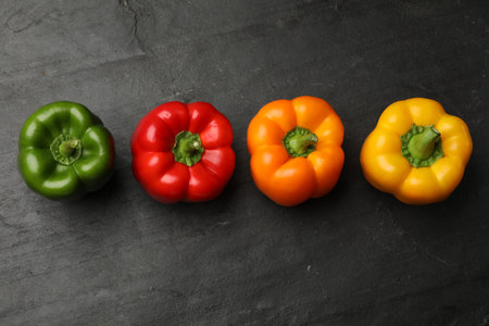 Fresh colorful bell peppers on black textured table, flat layの写真素材
