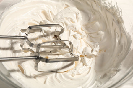 Whisks and whipped cream in bowl on table, top viewの写真素材