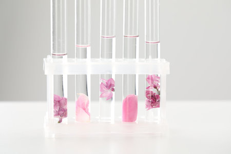 Making luxury perfume. Essential oils in test tubes and flowers on white table, closeupの写真素材