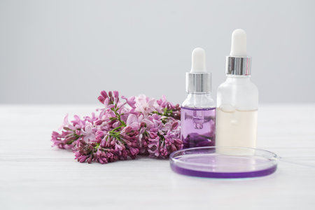 Making luxury perfume. Essential oils in glassware and flowers on white wooden table, closeupの写真素材