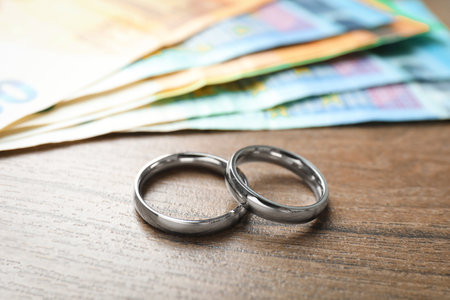 Silver wedding rings and euro banknotes on wooden table, closeupの写真素材