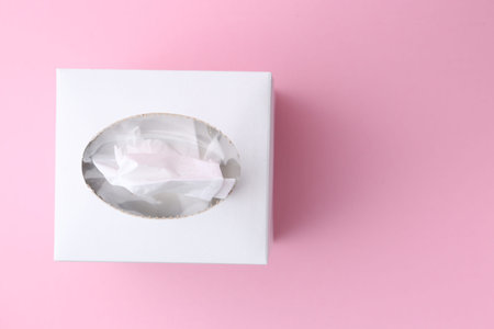 Box with paper handkerchiefs on pink background, top view. Space for textの写真素材
