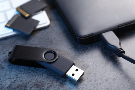 SD memory cards, USB flash drive, hard disk drive with cable and keyboard on dark grey table, closeupの写真素材
