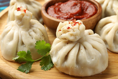 Delicious khinkali served with sauce on wooden plate, closeupの写真素材