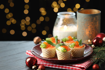Tasty canapes and festive decor on black table against blurred lights, closeup. Bokeh effectの写真素材