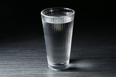 Fresh water in glass on dark wooden table