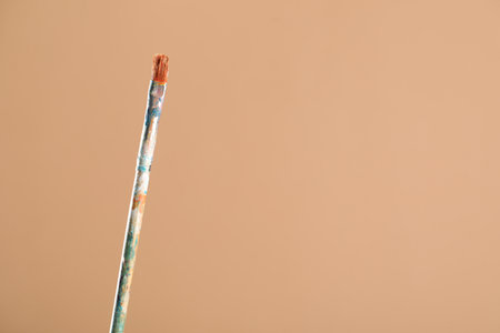 Dirty paintbrush on light brown background, closeup. Space for textの写真素材
