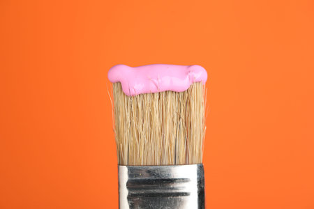 Brush with pink paint on orange background, closeupの写真素材