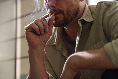 Man smoking cigarette on blurred background, closeupの写真素材