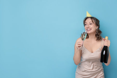 Birthday celebration. Woman with sparkling wine on light blue background. Space for textの写真素材
