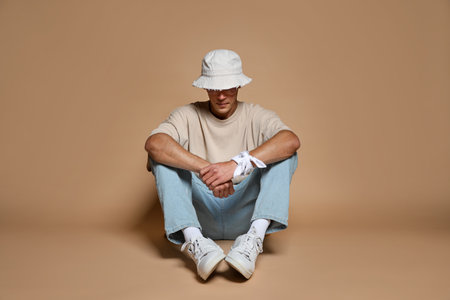 Fashionable portrait of handsome man in stylish outfit on brown backgroundの写真素材