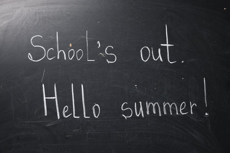 Phrases School's Out and Hello Summer with exclamation mark on blackboardの写真素材