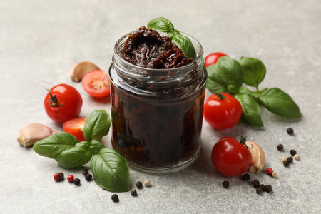 Delicious sun dried tomatoes, fresh vegetables, basil and garlic on light grey table, closeupの写真素材