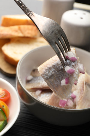 Eating delicious herring with onions at black table, closeupの写真素材