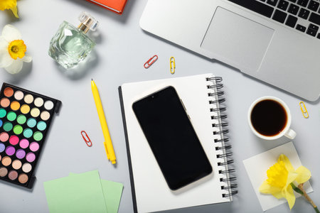 Flat lay composition with stationery, phone, coffee and flowers on light grey background