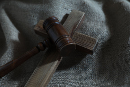 Judge's gavel and wooden cross on burlap fabric, closeupの写真素材
