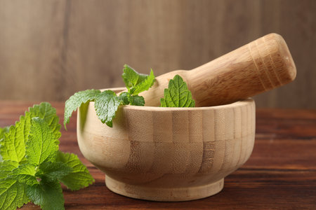 Fresh lemon balm leaves, pestle and mortar on wooden table, closeupの写真素材