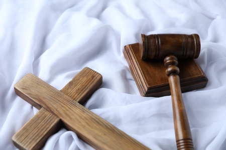 Judge's gavel and wooden cross on white fabric, above viewの写真素材