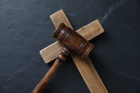 Judge's gavel and wooden cross on black table, top viewの写真素材