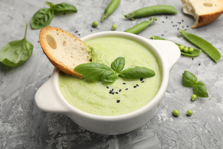 Tasty pea cream soup with basil and crouton served on grey table, closeupの写真素材