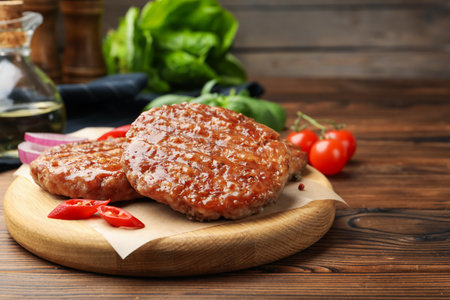 Delicious hamburger patties and spices on wooden table, closeup. Space for textの写真素材