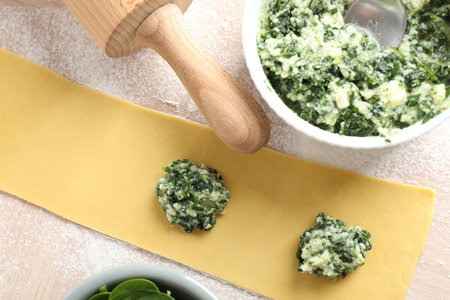 Making ravioli with cottage cheese and spinach at light table, flat layの写真素材