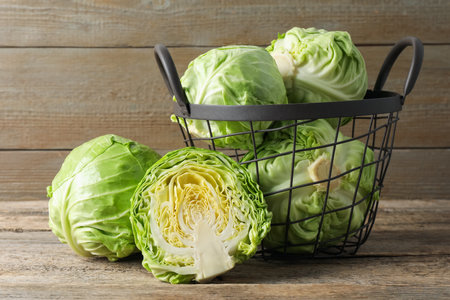 Fresh cabbages and basket on wooden table, closeupの写真素材