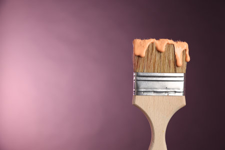 Brush with paint on pink background, closeup. Space for textの写真素材