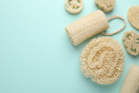 Natural loofah sponges on light blue background, flat lay. Space for textの写真素材
