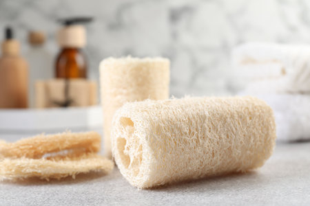 Different loofah sponges and cosmetic products on light grey table, closeupの写真素材