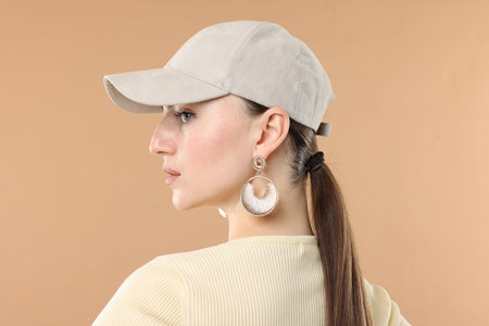 Beautiful woman in stylish baseball hat on beige backgroundの写真素材