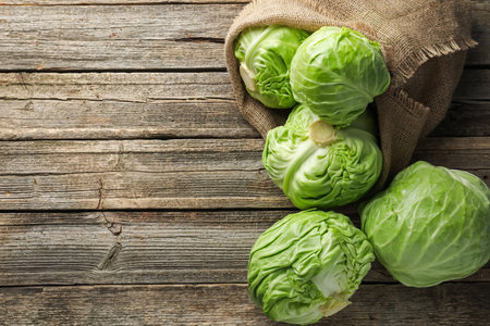 Fresh whole cabbages on wooden table, flat lay. Space for textの写真素材