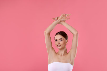 Young woman showing smooth skin after epilation on pink backgroundの写真素材