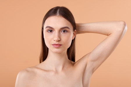 Young woman showing smooth skin after epilation on beige backgroundの写真素材