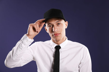 Young man in stylish baseball hat on dark blue background