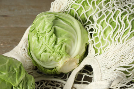 Fresh cabbages and net bag on wooden table, closeupの写真素材