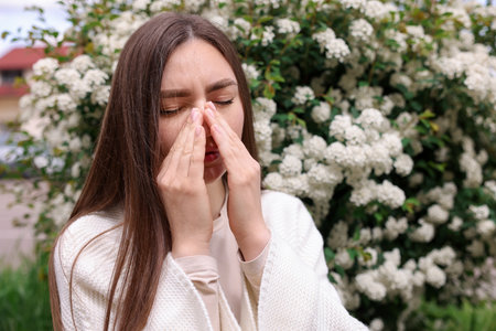 Woman suffering from seasonal pollen allergy near blossoming shrub on spring day, space for textの写真素材